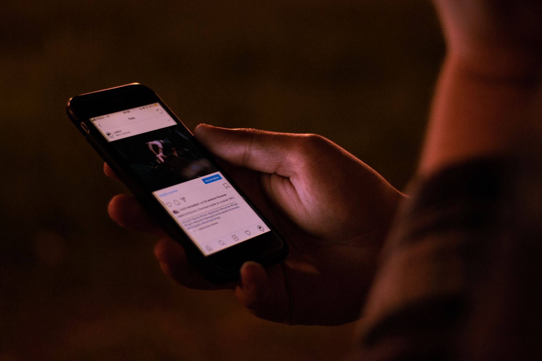 Person scrolling a smartphone in a dim room